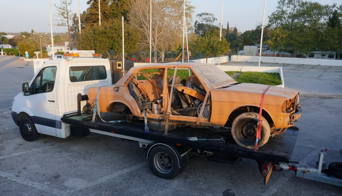 Tow truck transporting an old rusty car, representing the Nova Junk Cars brand