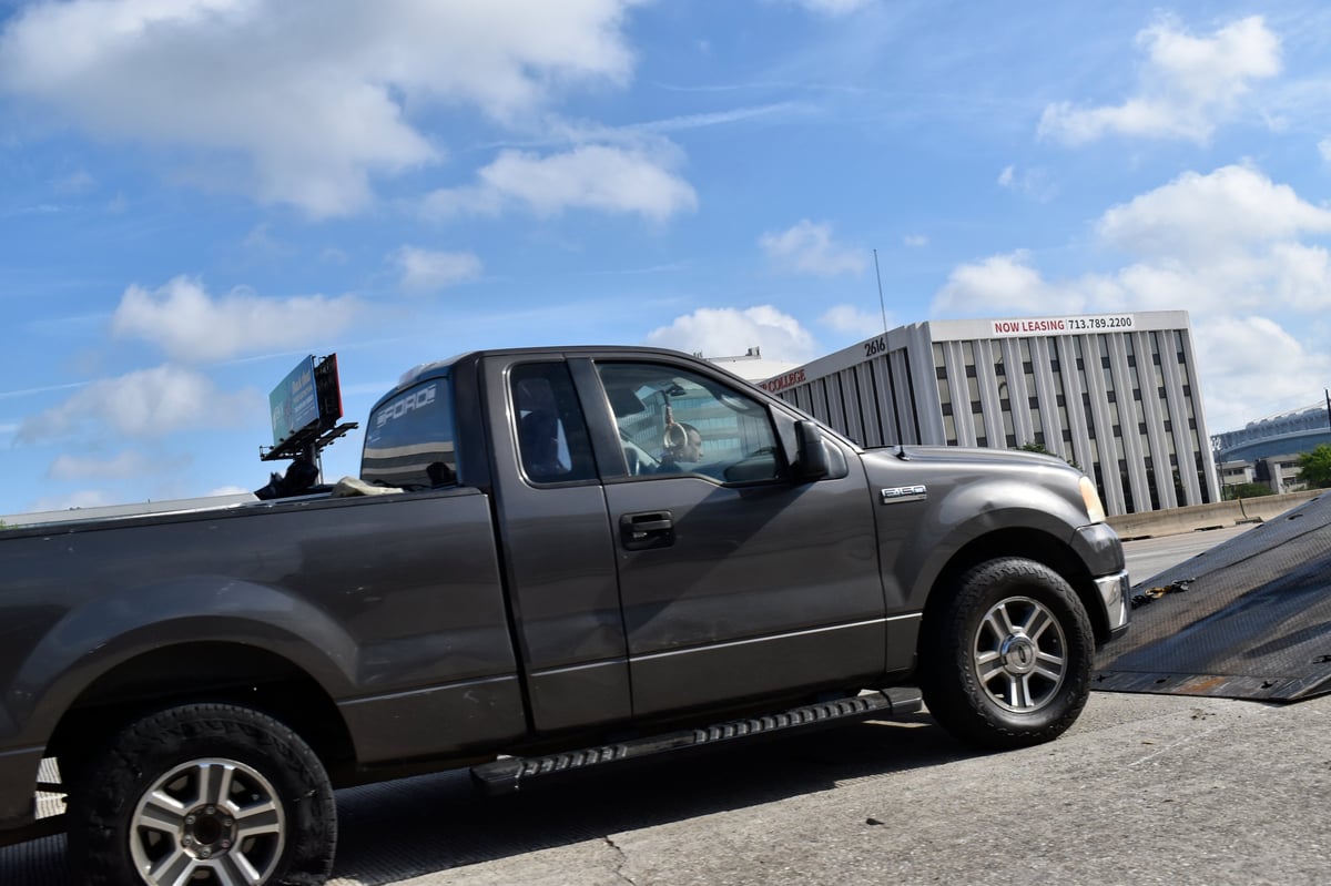 Flatbed tow truck recovering a disabled vehicle on a highway, representing the BlackHorn Towing brand
